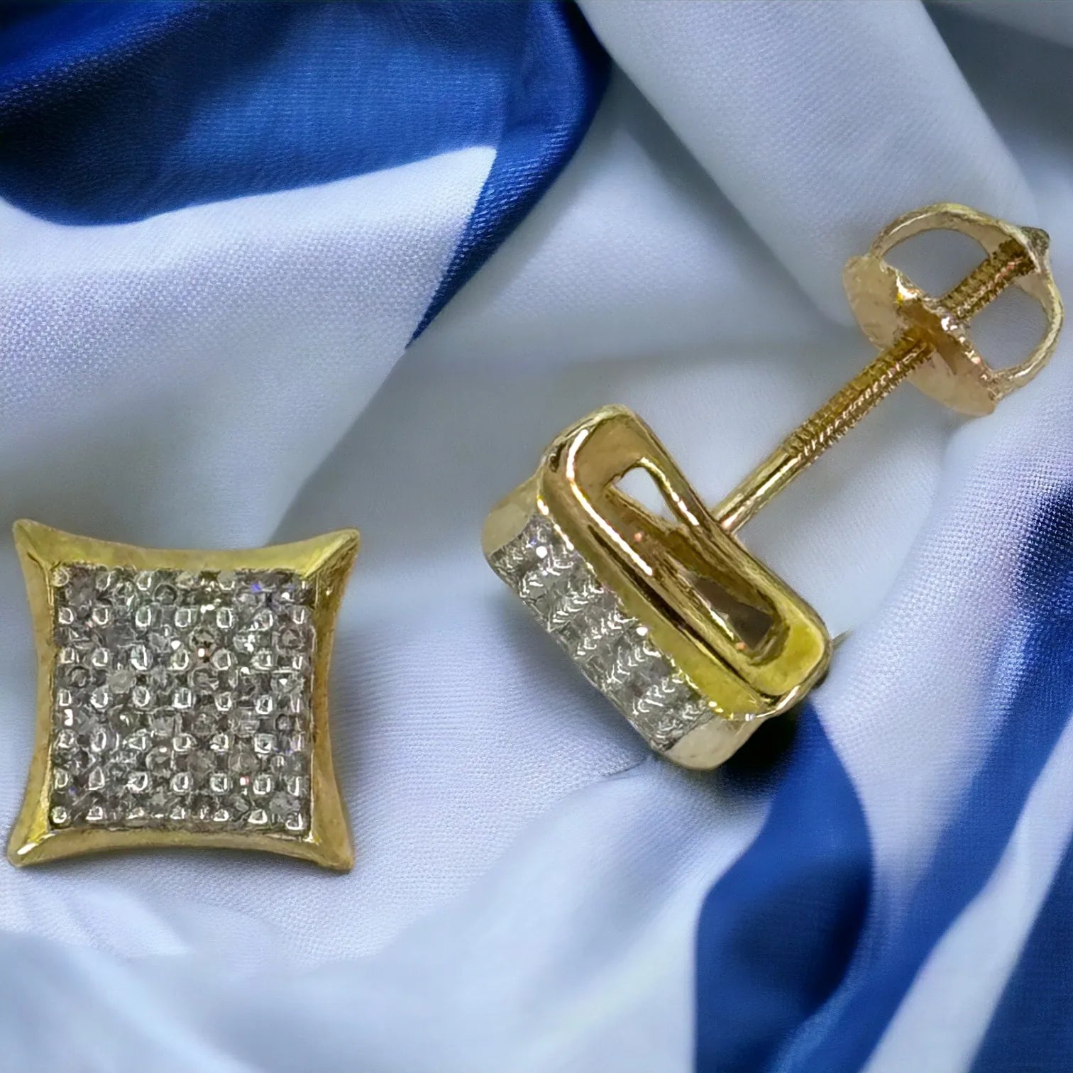 Angled close-up of men's 10KT yellow gold 8mm square diamond earrings with 0.25 carat total SI diamonds, highlighting the deep concave design and polished beveled edges on blue-white fabric