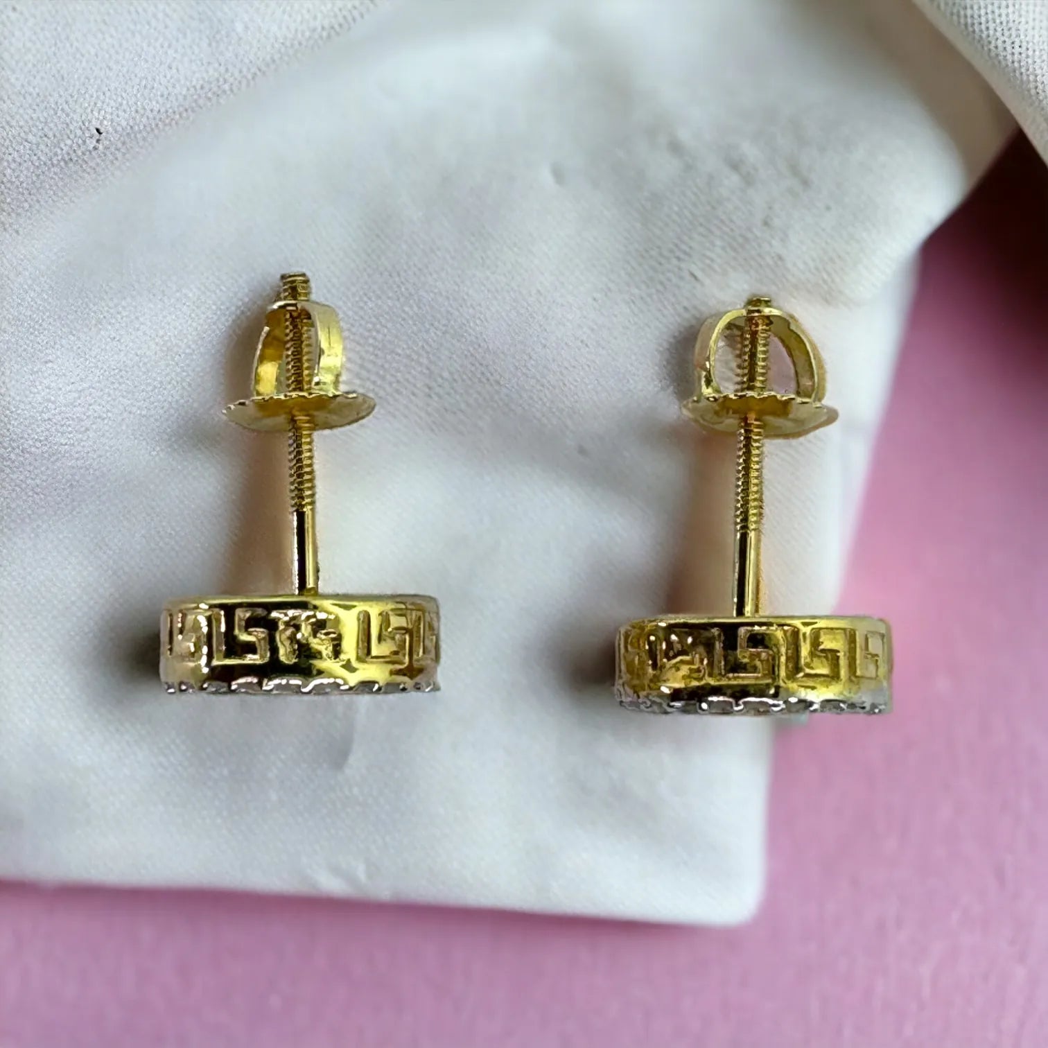 Top view of 10KT yellow gold 9mm round Ankh cross stud earrings with 0.15ct total SI diamonds, showing secure screw-back posts and "10KT" hallmark on white-pink fabric