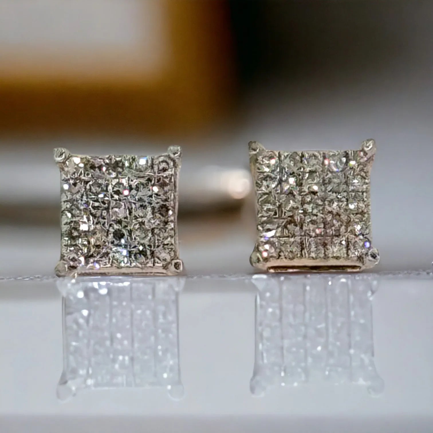 Front-facing 10KT gold 6mm square micro-pave diamond stud earrings with 0.26 carat total SI diamonds, displayed upright on reflective surface to highlight intense sparkle and fire