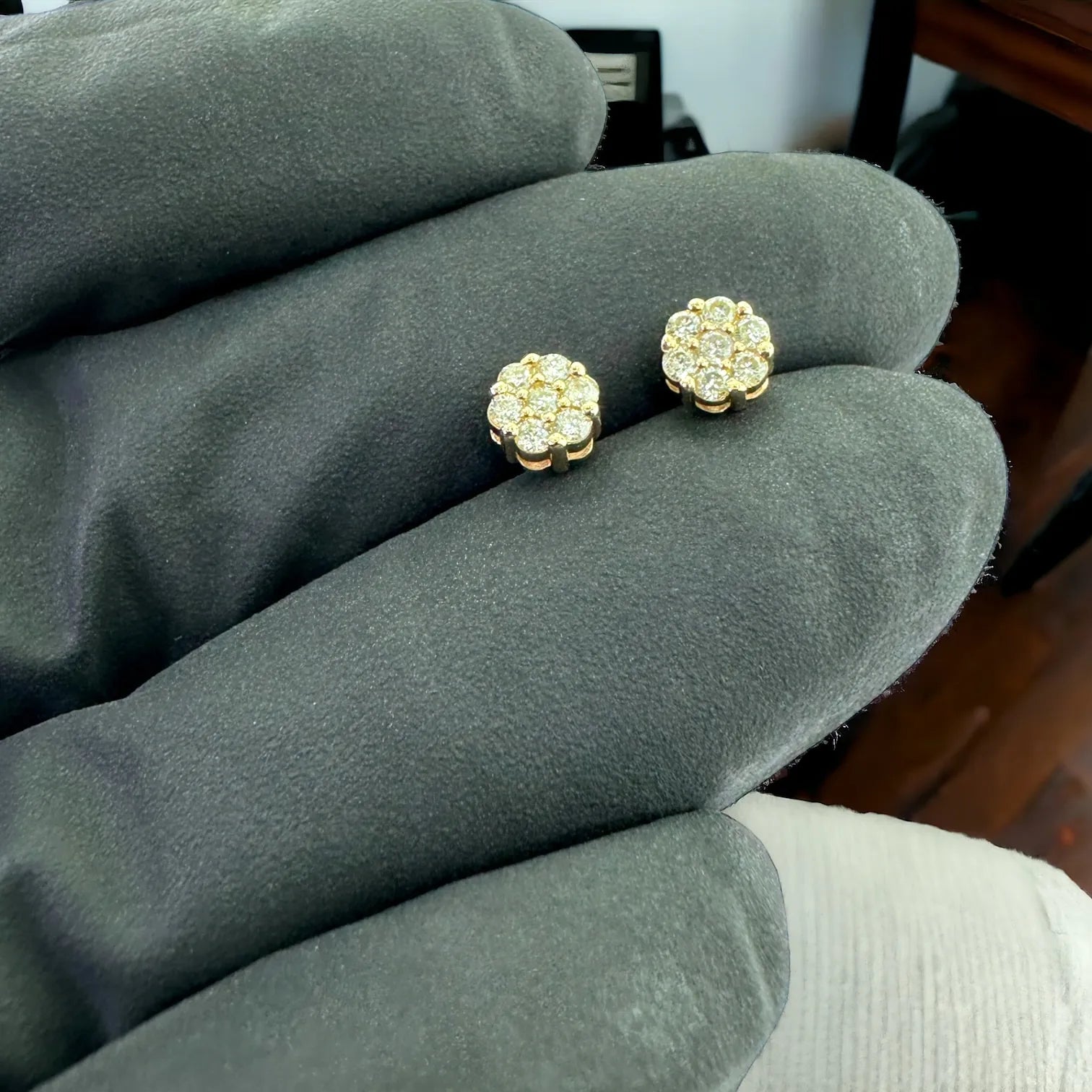 Close-up of genuine 10K yellow gold diamond cluster earrings 0.25ct SI clarity, 5mm flower design displayed on black glove