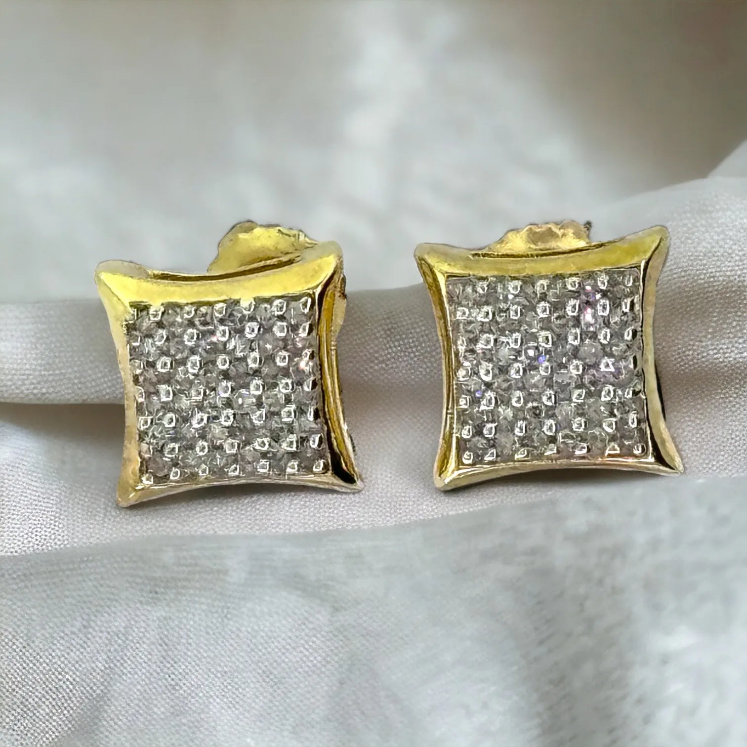Top and partial back view of men's 10KT gold 8mm square micro-pave diamond earrings (0.25ct total SI diamonds) with secure screw-back closures visible on light fabric