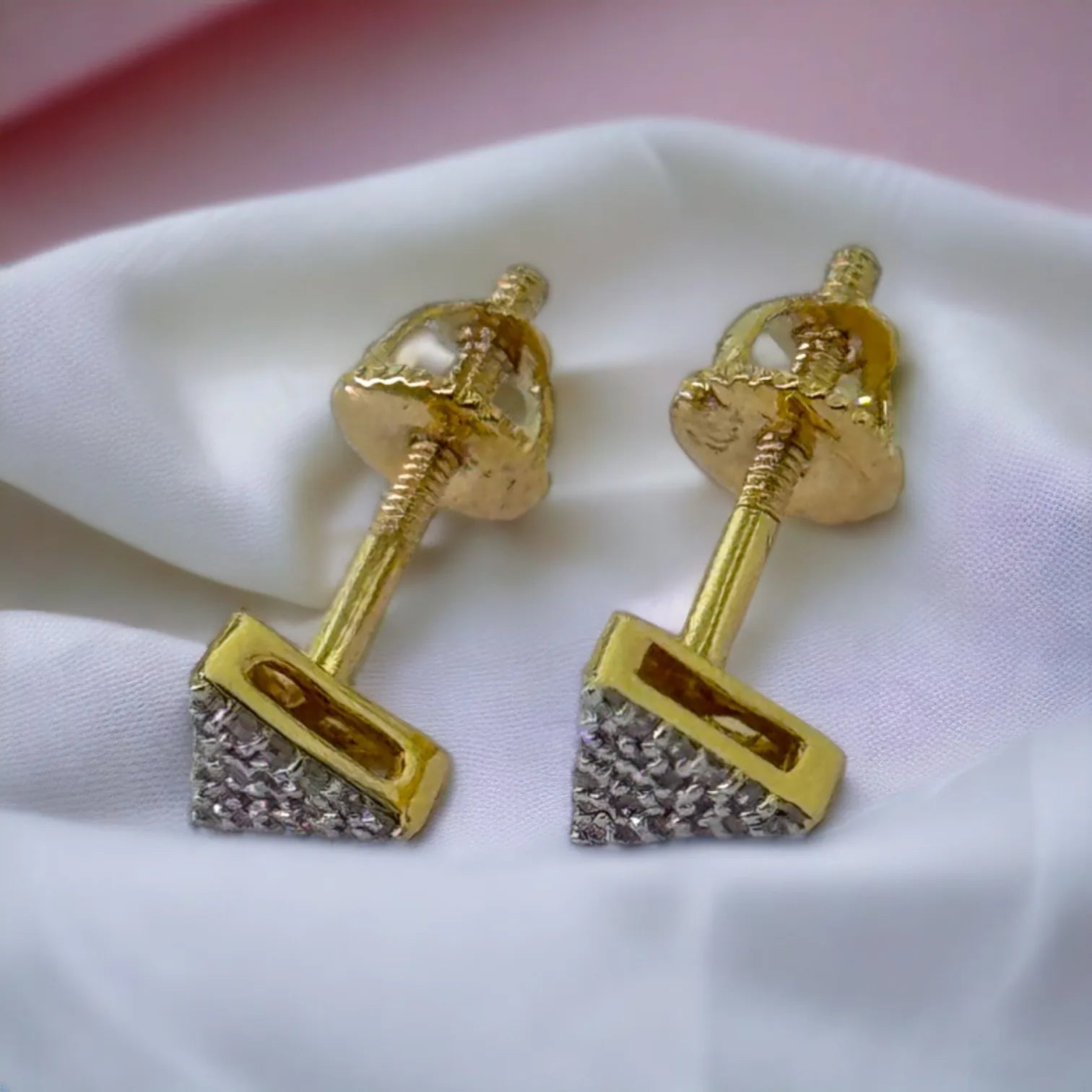 Delicate 10KT gold triangle diamond stud earrings (0.09ct SI clarity) held in hand to showcase petite 5mm size and brilliant pave sparkle