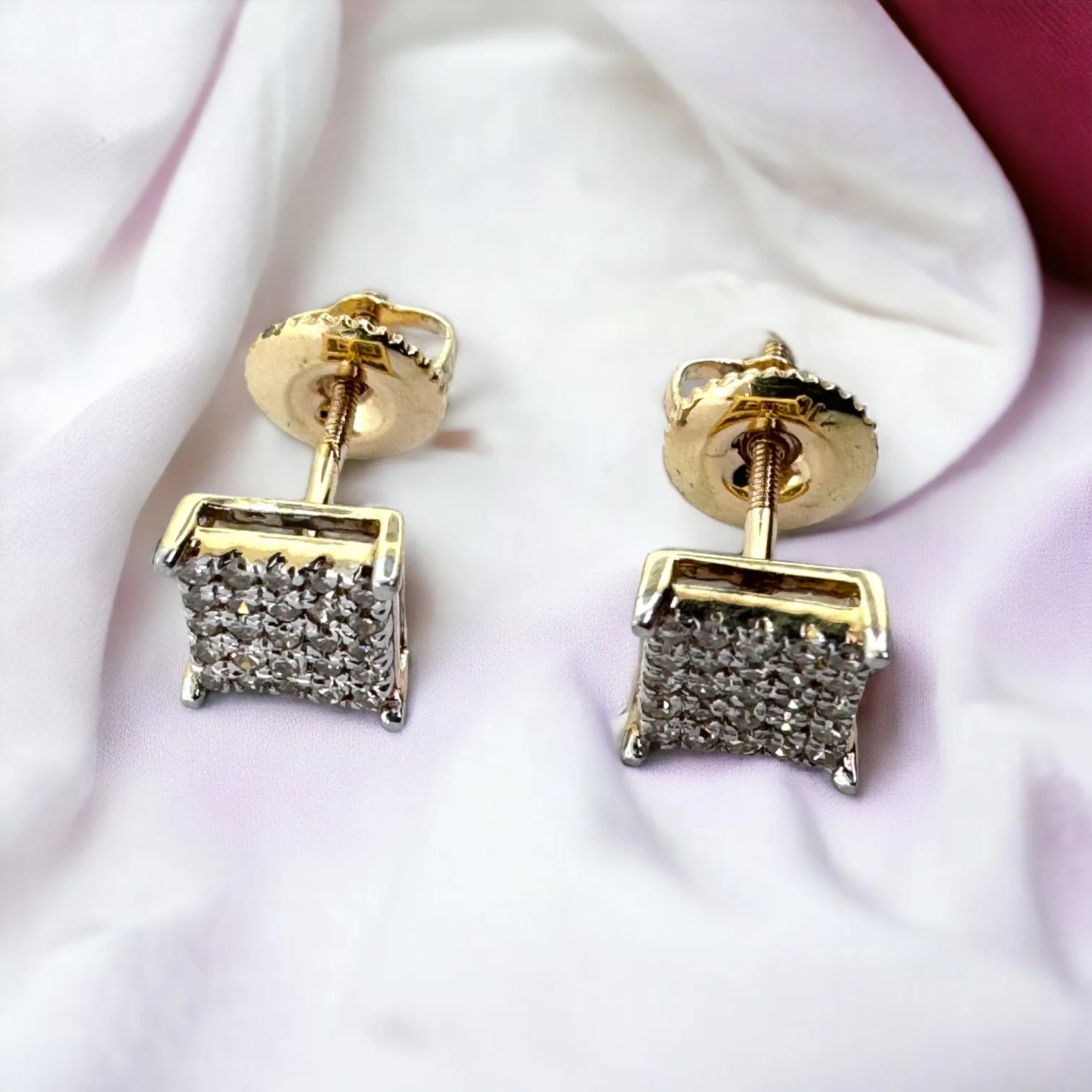 Close-up of 10KT yellow gold 6mm square diamond studs totaling 0.26ct SI diamonds, shown from side and back with screw-back closures on light fabric